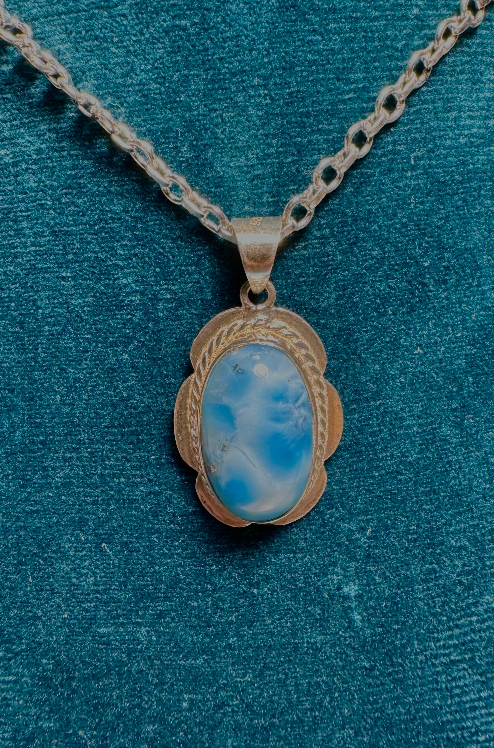 Necklace with a pendant featuring a blue stone on a textured blue background